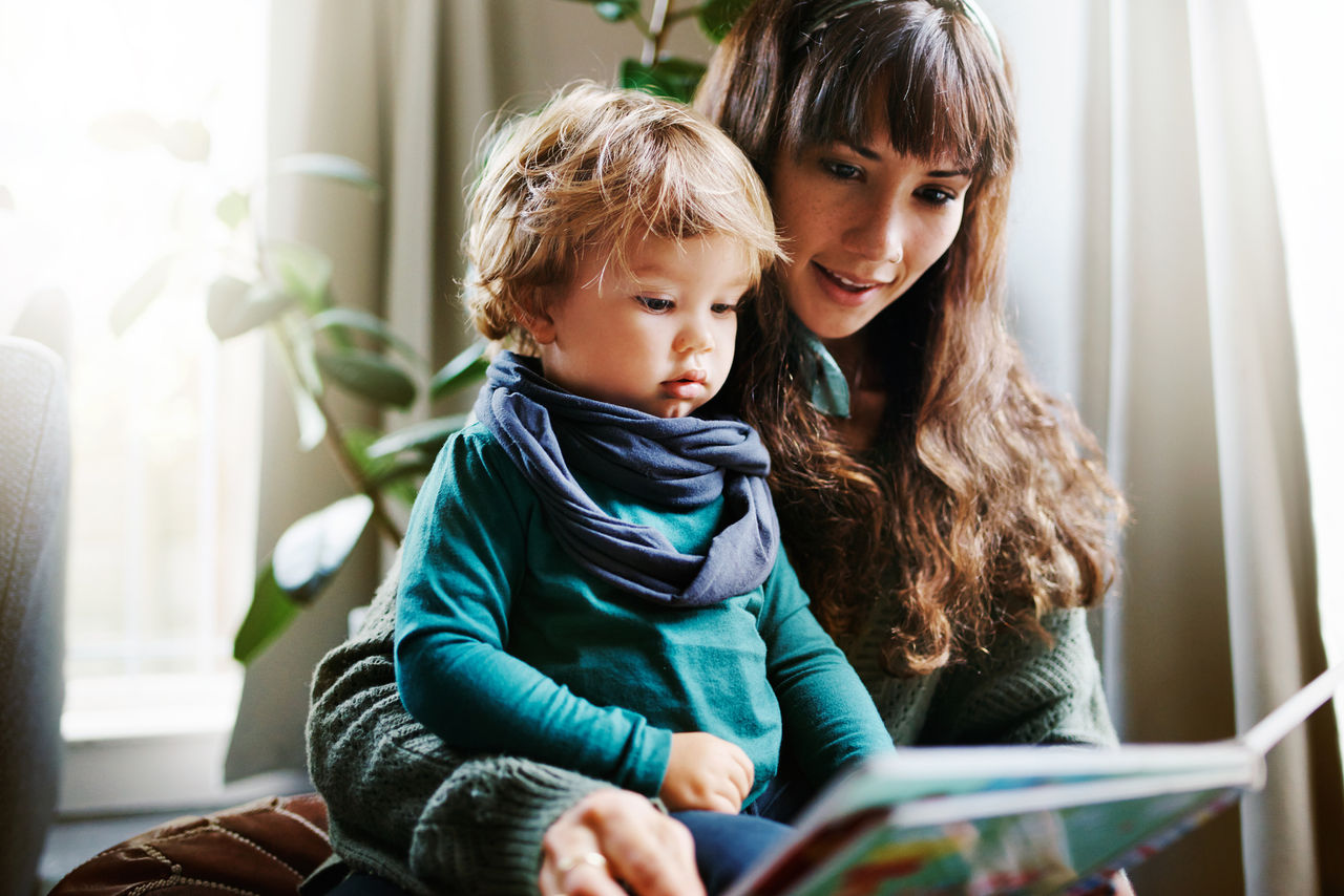 Toddler looking at a book with his mother