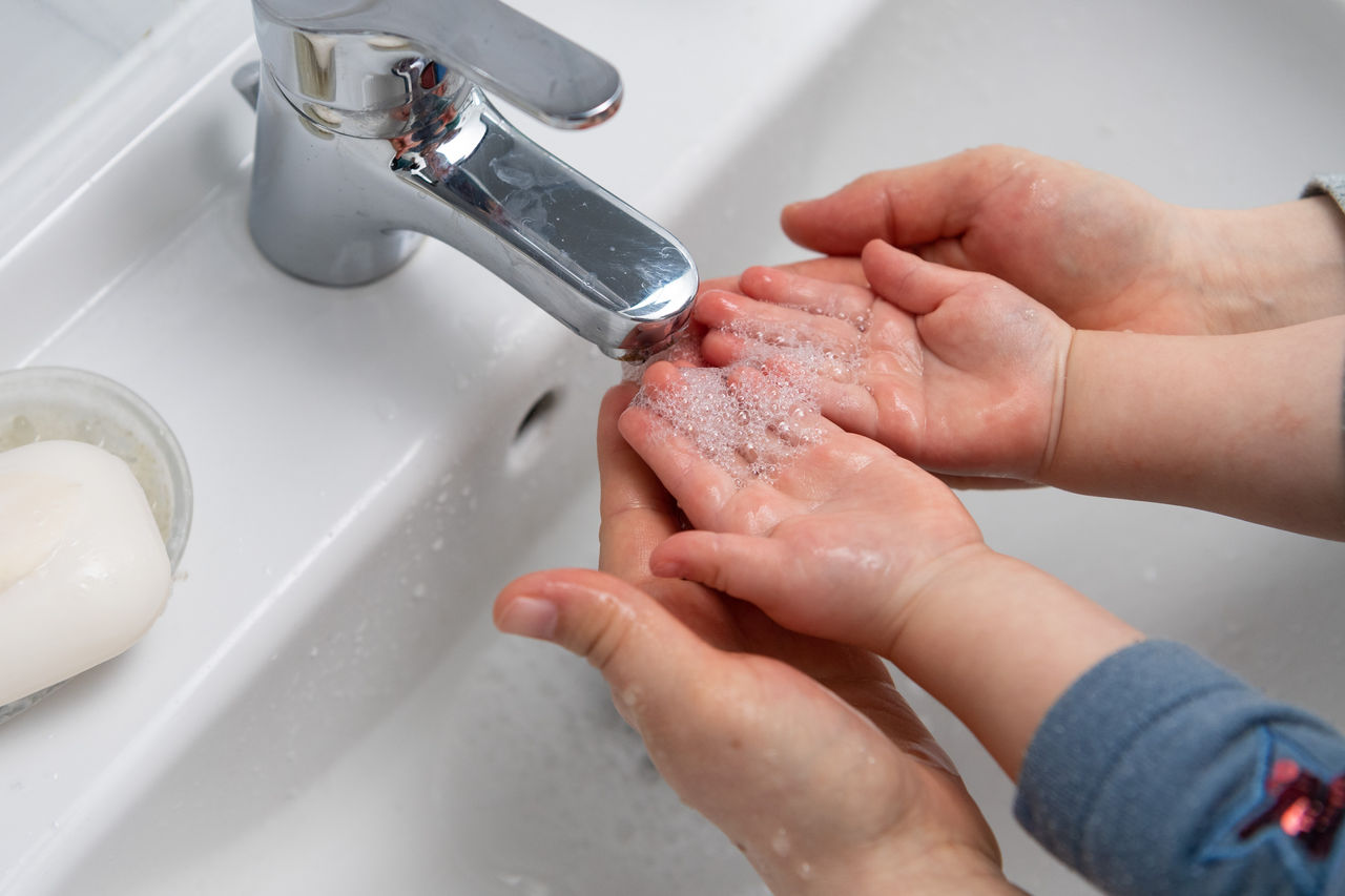 Kleinkind und Mutter waschen zusammen Hände