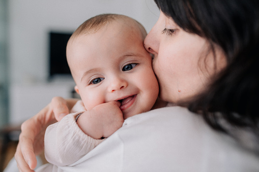 Mother kissing laughing baby