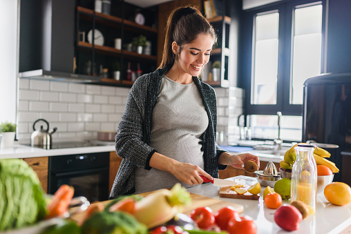 Une femme enceinte est allongée sur le canapé et tient une pomme dans la main