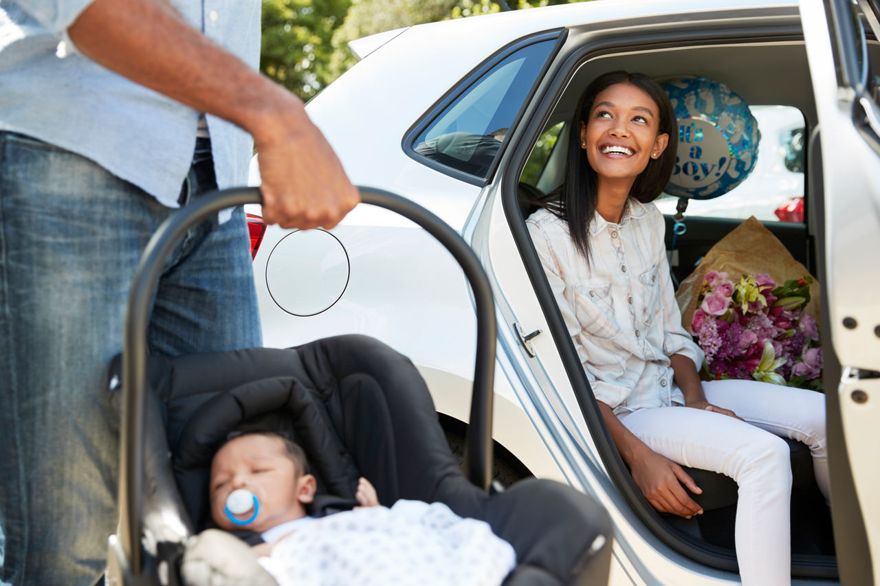 Parents Bringing Newborn Baby Home In Car